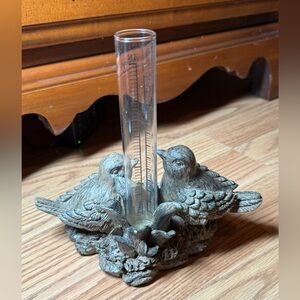 A decorative sweet bird-themed rain gauge, often used as garden or home decor
